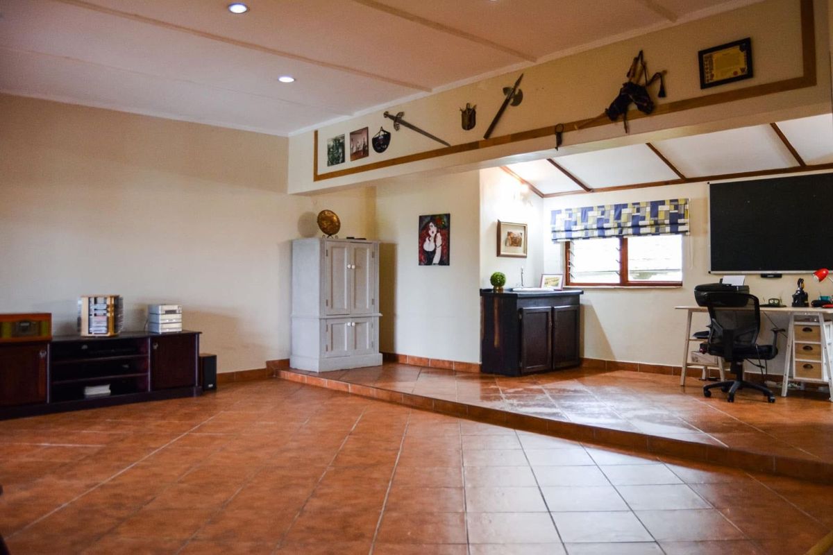 Spacious living area featuring a raised platform section, tiled flooring, recessed ceiling lighting, and a built-in storage cabinet.