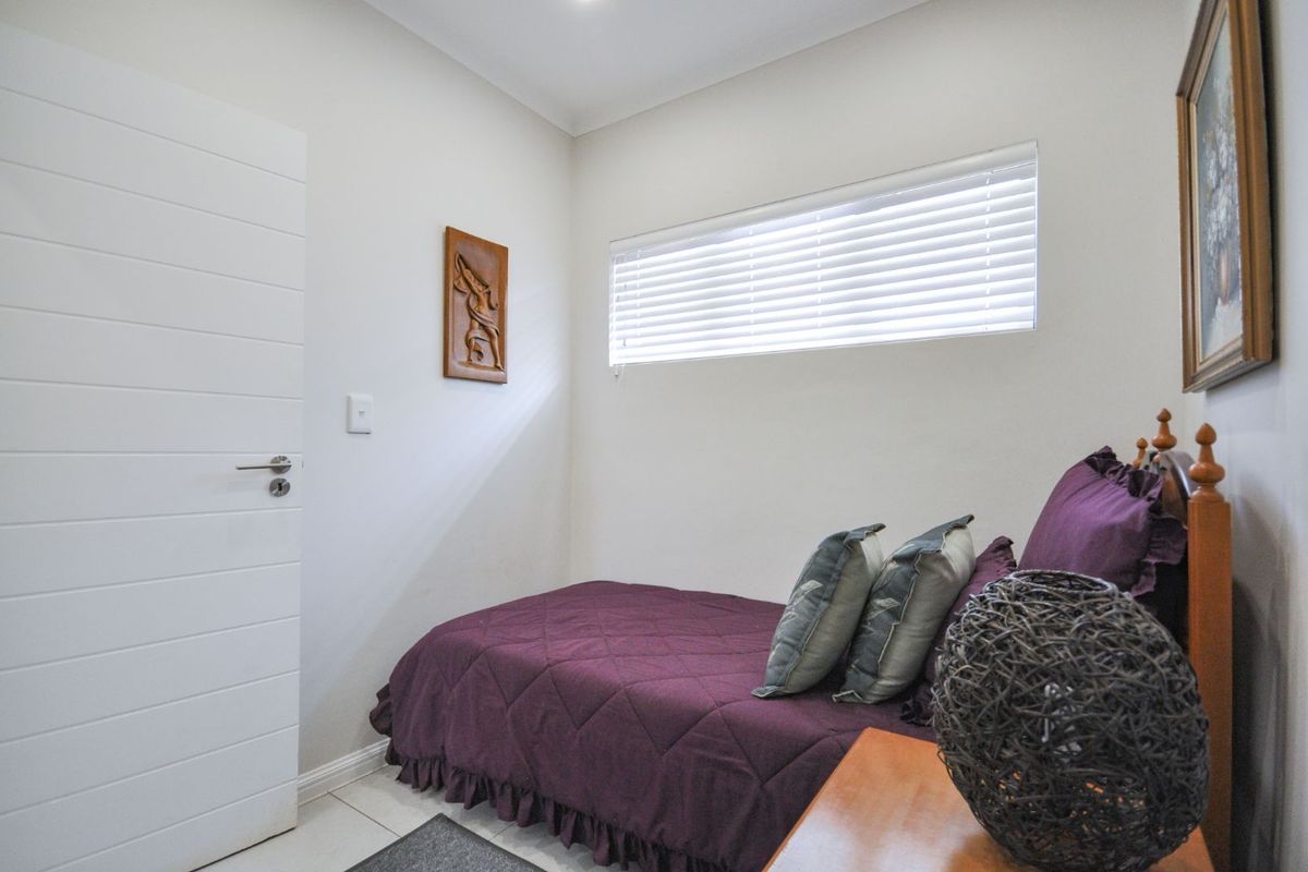 A compact bedroom featuring neutral walls, tiled flooring, and horizontal window blinds, providing a clean and functional living space.