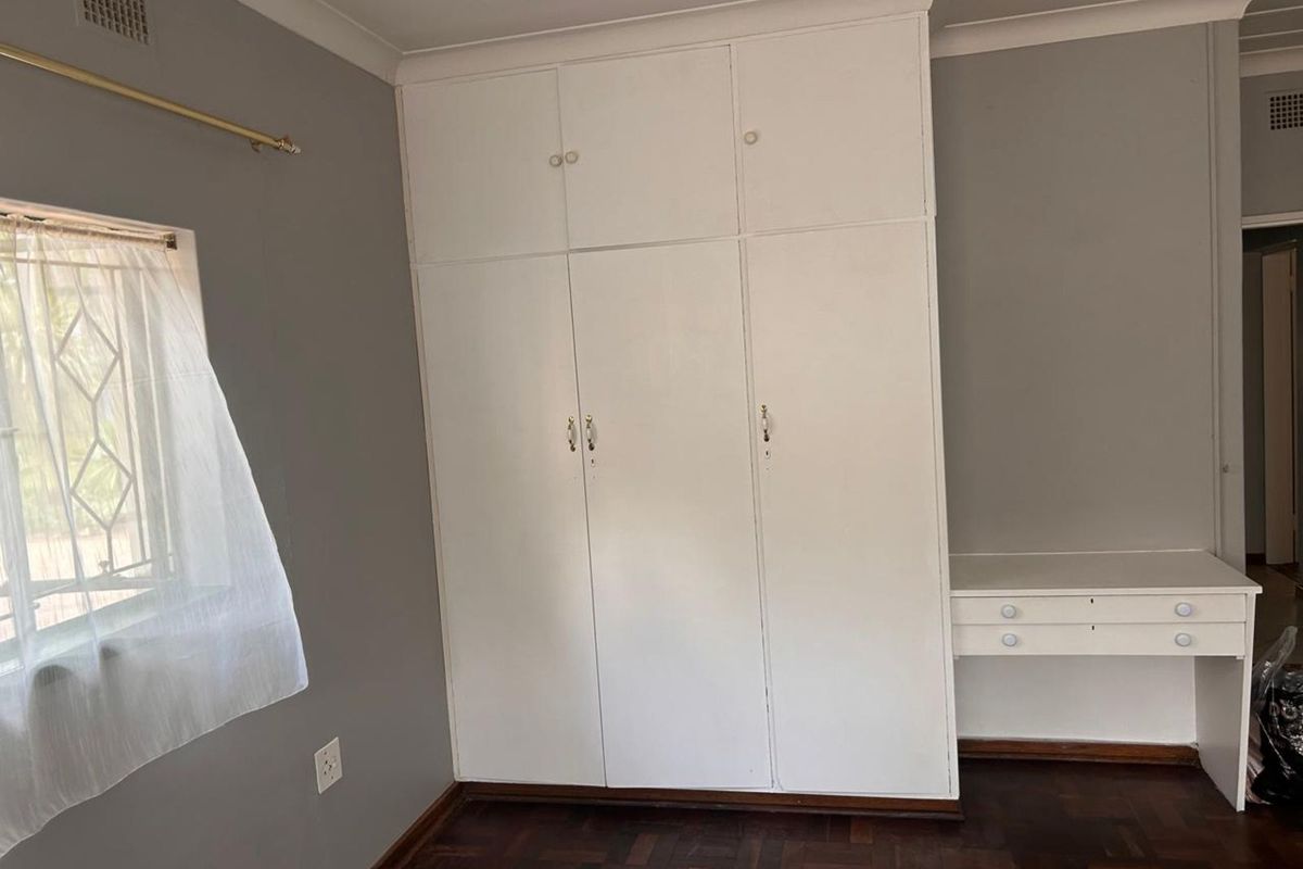 Bedroom featuring built-in floor-to-ceiling cabinetry with integrated vanity desk and classic parquet flooring.