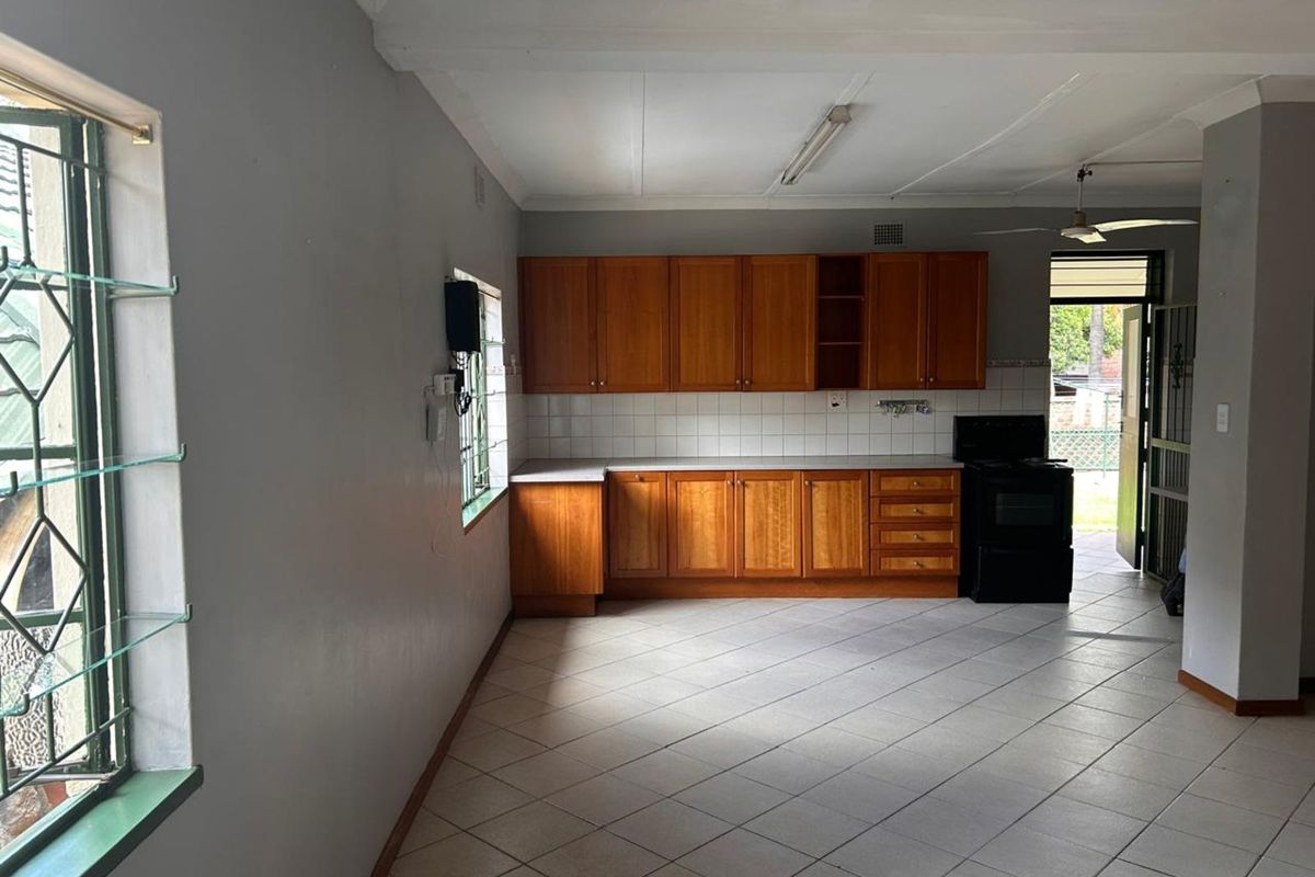 A functional kitchen featuring wooden cabinetry, tiled flooring, and a tiled backsplash, with direct access to the exterior.