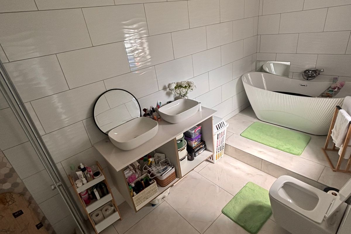 Modern bathroom featuring a raised platform with a freestanding bathtub, a double vanity with vessel sinks, and a separate glass-enclosed shower area.