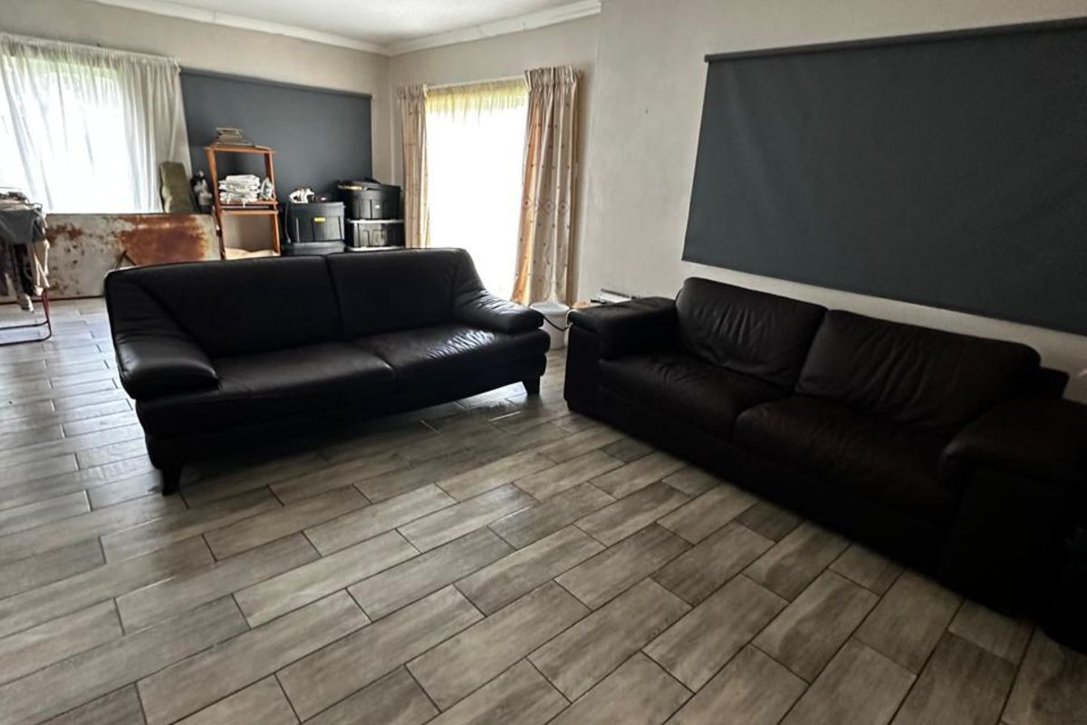 Spacious living room featuring modern wood-look floor tiles and neutral wall finishes, offering a versatile layout for comfortable family living.