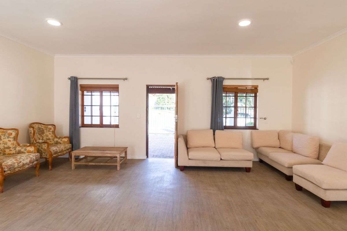 Spacious living room featuring wood-look flooring, recessed ceiling lighting, and timber-framed windows, providing a bright and functional living space.