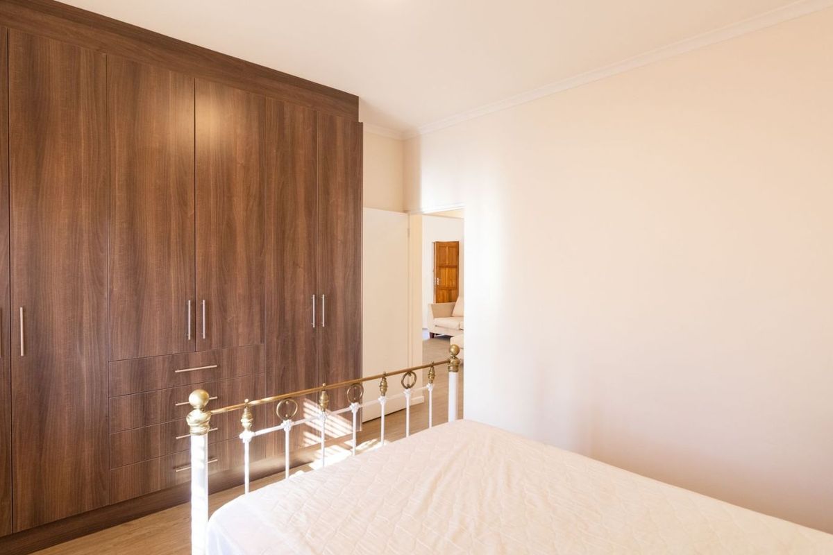 A well-maintained bedroom featuring extensive built-in wooden cabinetry and light-toned flooring, offering a clean and functional living space.
