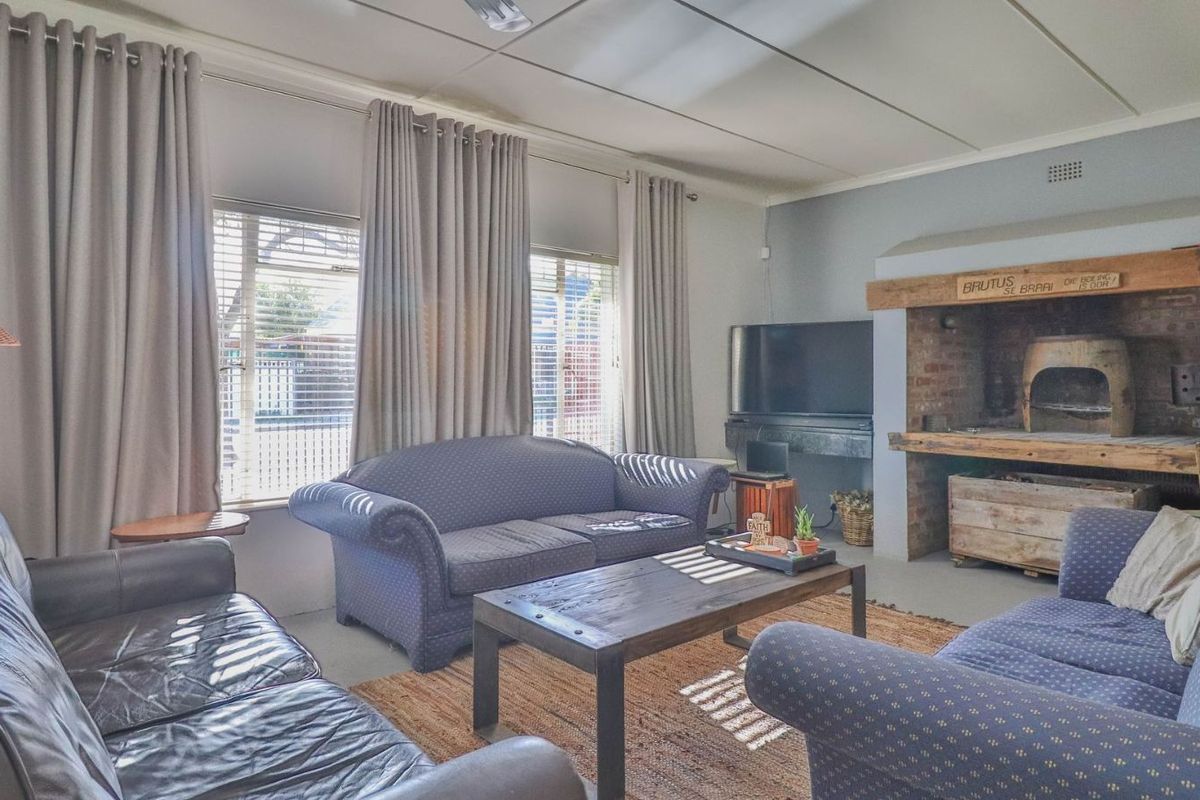Spacious living room featuring a large built-in brick fireplace, tiled ceiling, and large windows allowing for ample natural light.