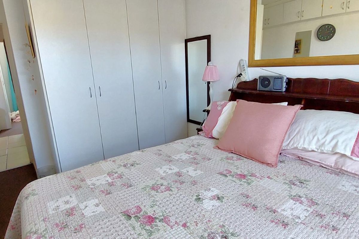 A bedroom featuring built-in cupboards and overhead storage units, providing ample storage space within the room.