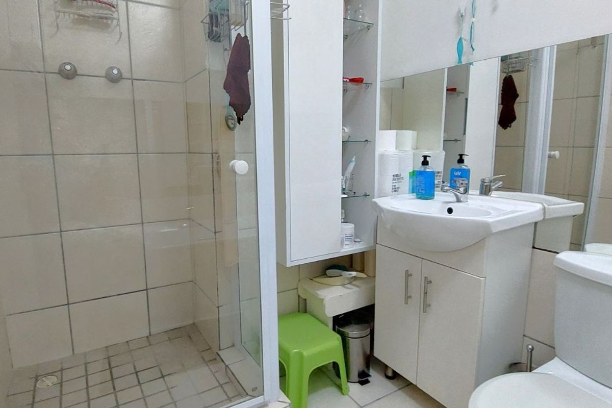 Compact bathroom featuring a glass-enclosed shower, white vanity cabinet with integrated basin, and a standard toilet.