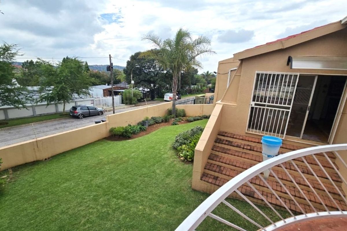 Elevated view of the townhouse exterior featuring a private garden, brick staircase, and security gate access to the main living area.