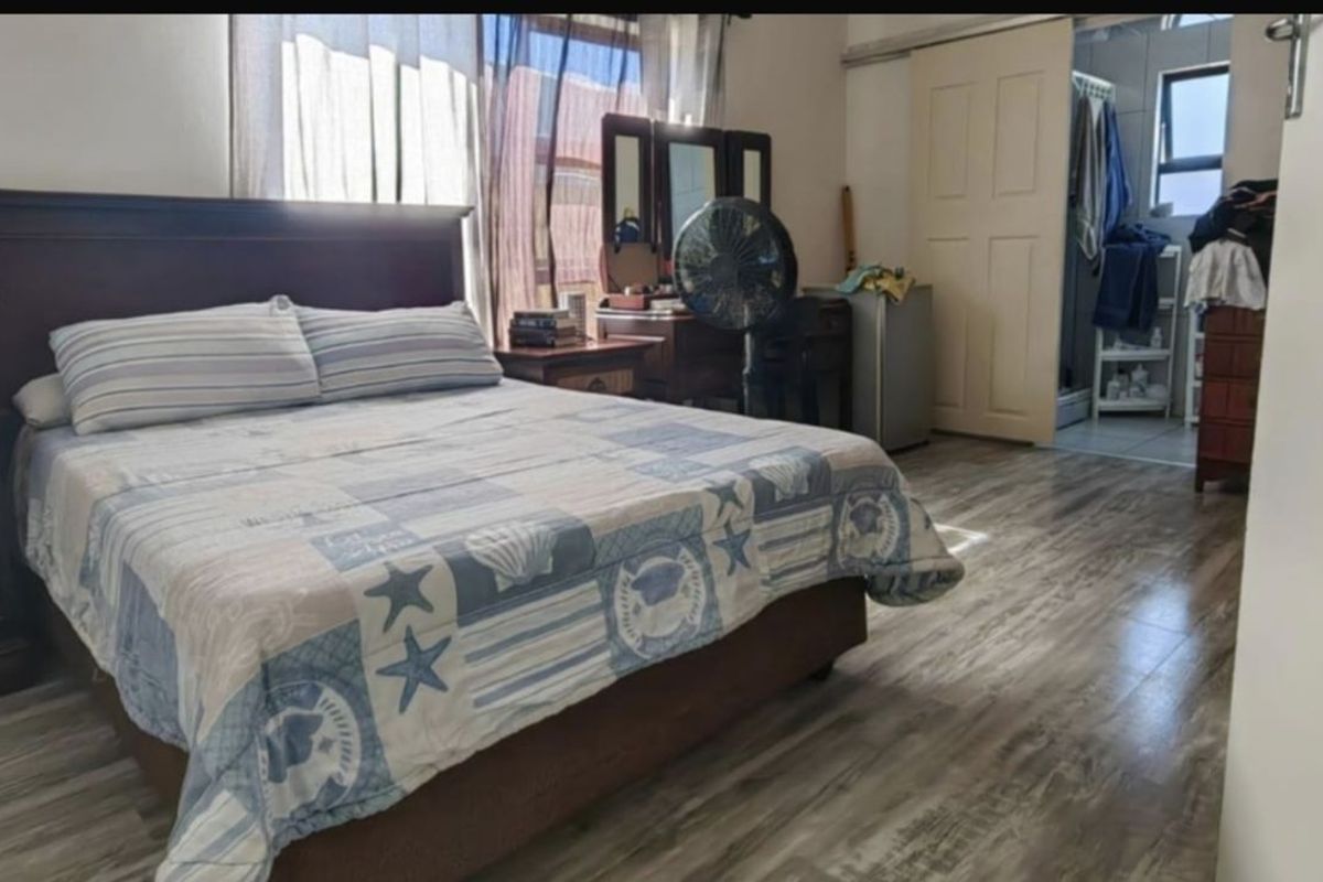 A bedroom featuring wood-look laminate flooring and an en-suite bathroom accessible through a sliding door.