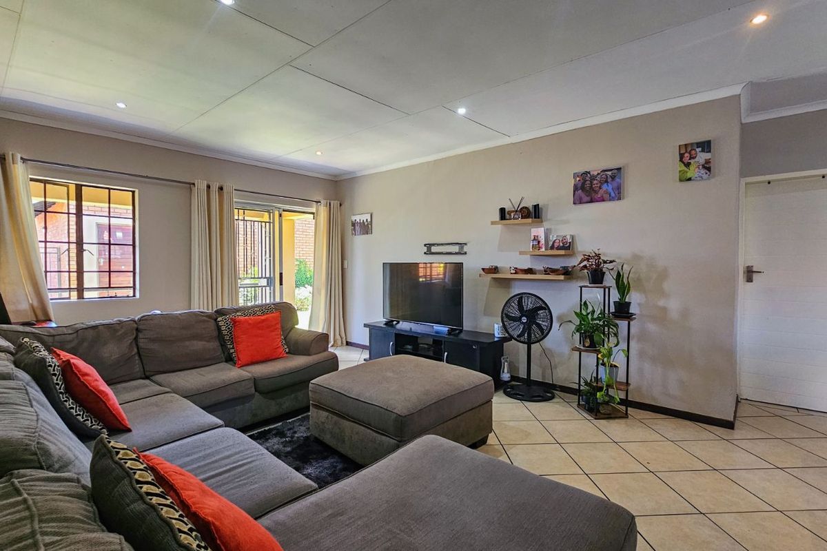 A spacious living room featuring tiled flooring, recessed ceiling lighting, and sliding glass doors providing access to the exterior.