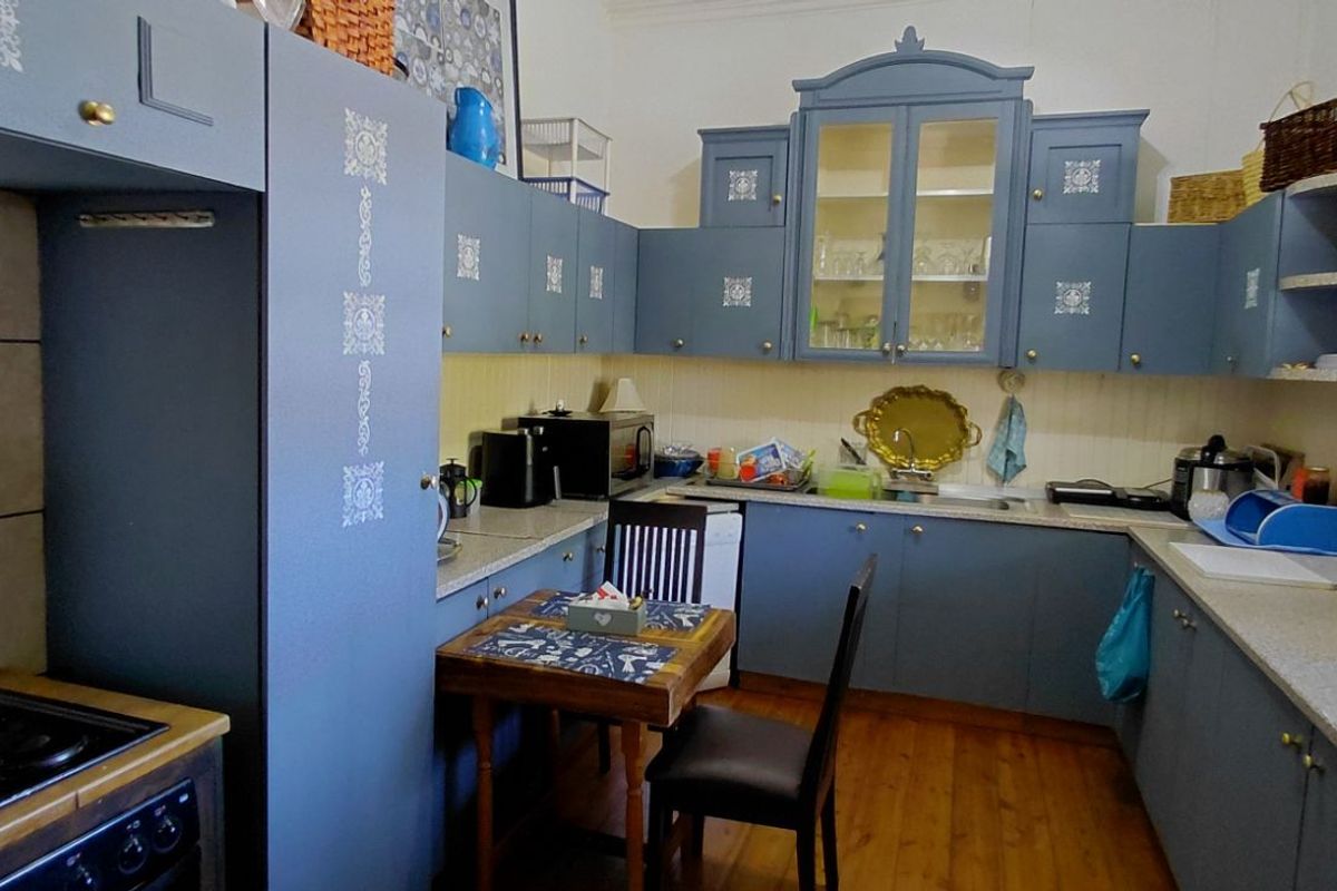 A functional kitchen featuring blue cabinetry, laminate countertops, a built-in stove, and timber flooring, offering a classic aesthetic with ample storage space.