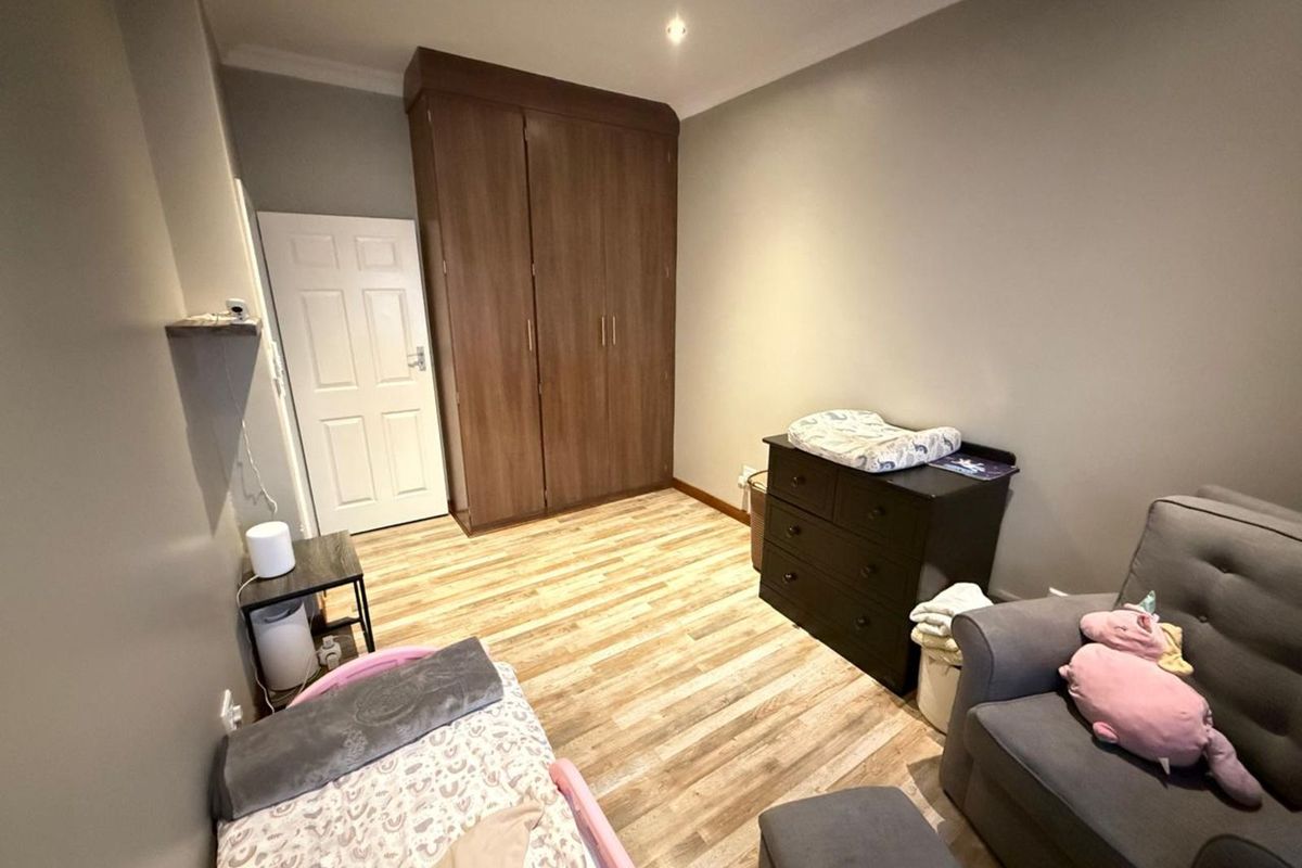 A bedroom featuring wood-look laminate flooring, built-in wooden cupboards, and a standard interior door.