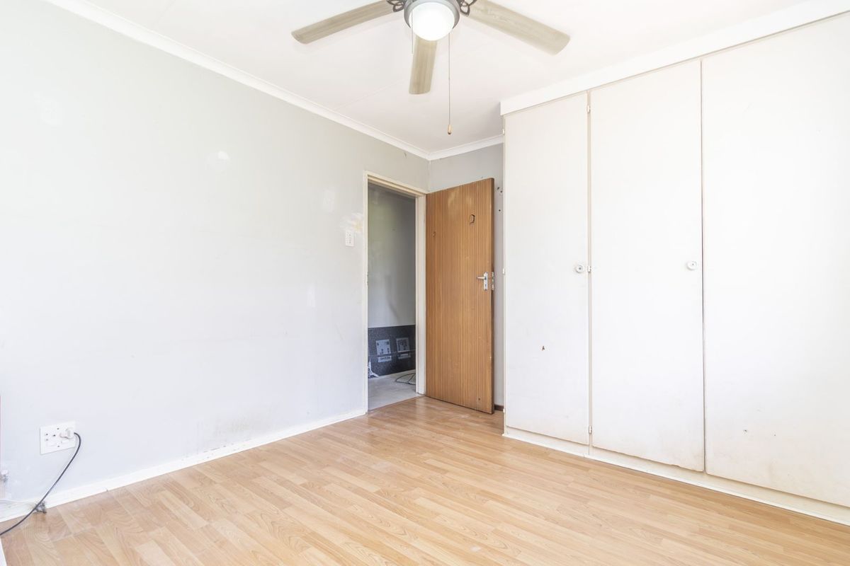 A bedroom featuring light wood-look laminate flooring, built-in cupboards, and a ceiling fan.