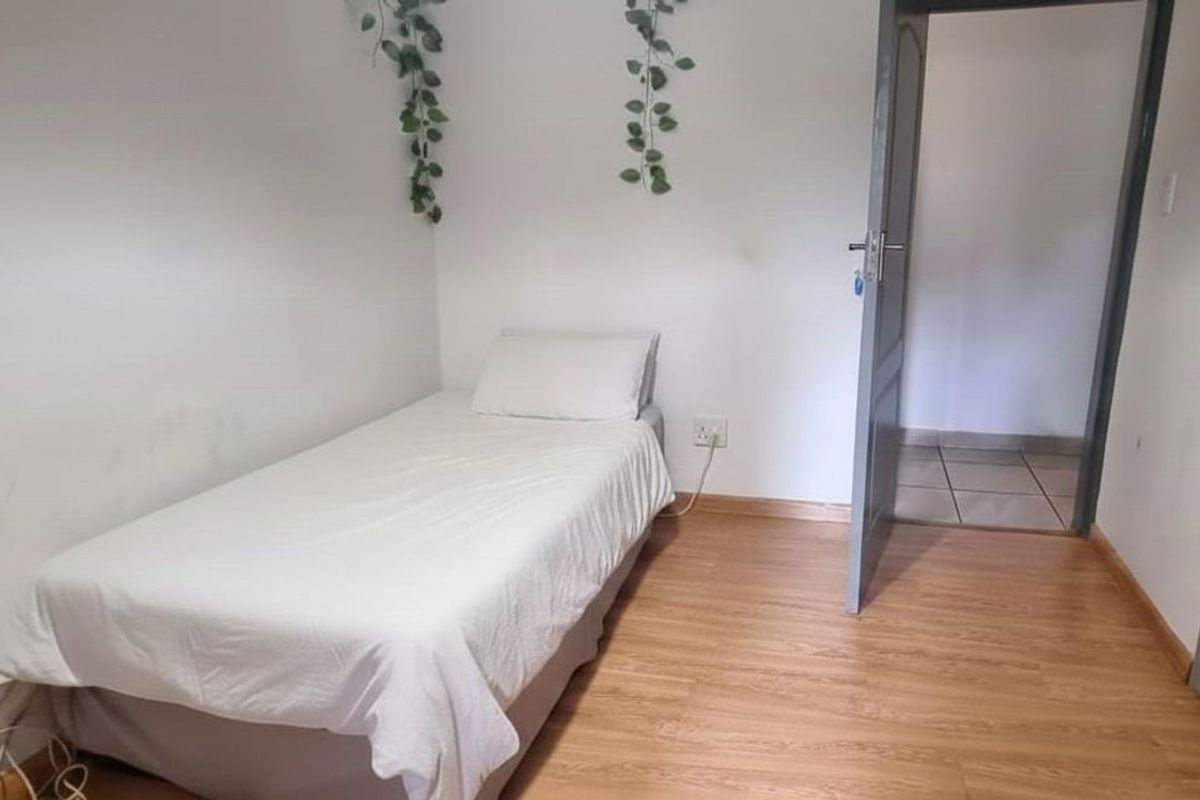 A simple bedroom featuring light wood-look flooring and a standard interior door leading to an adjacent space.