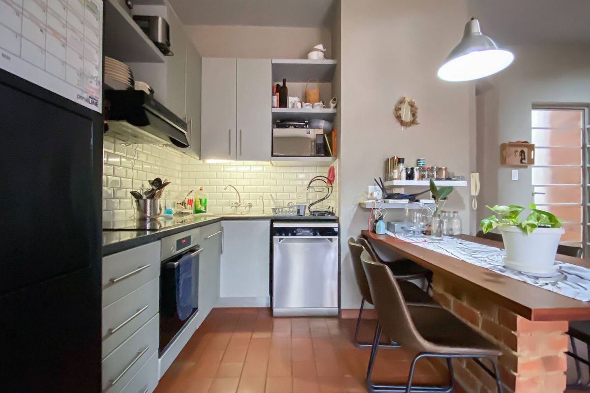Compact kitchen featuring subway tile backsplash, built-in cabinetry, integrated oven, extractor fan, and a breakfast bar with brick base.
