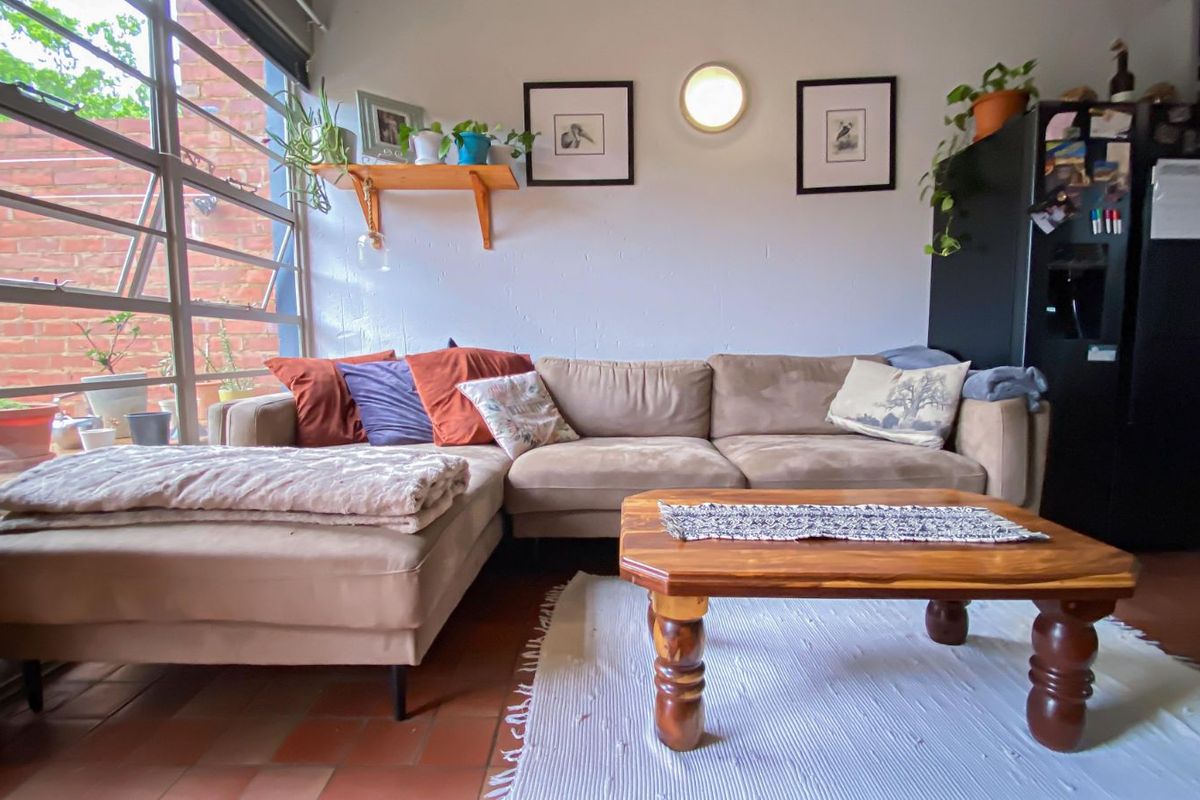 A comfortable living area featuring large windows that provide natural light and a view of the exterior brick wall.