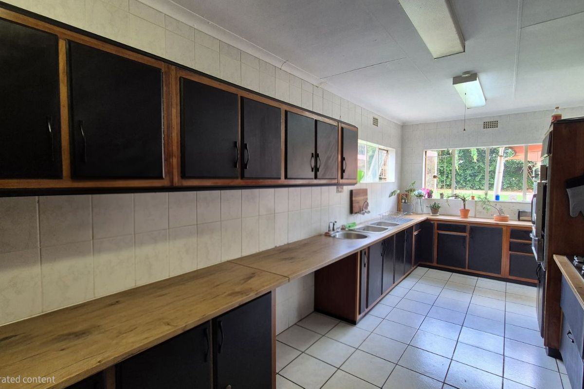 A functional kitchen featuring extensive wooden cabinetry, tiled splashbacks, a double sink, and a built-in gas hob with ample countertop workspace.