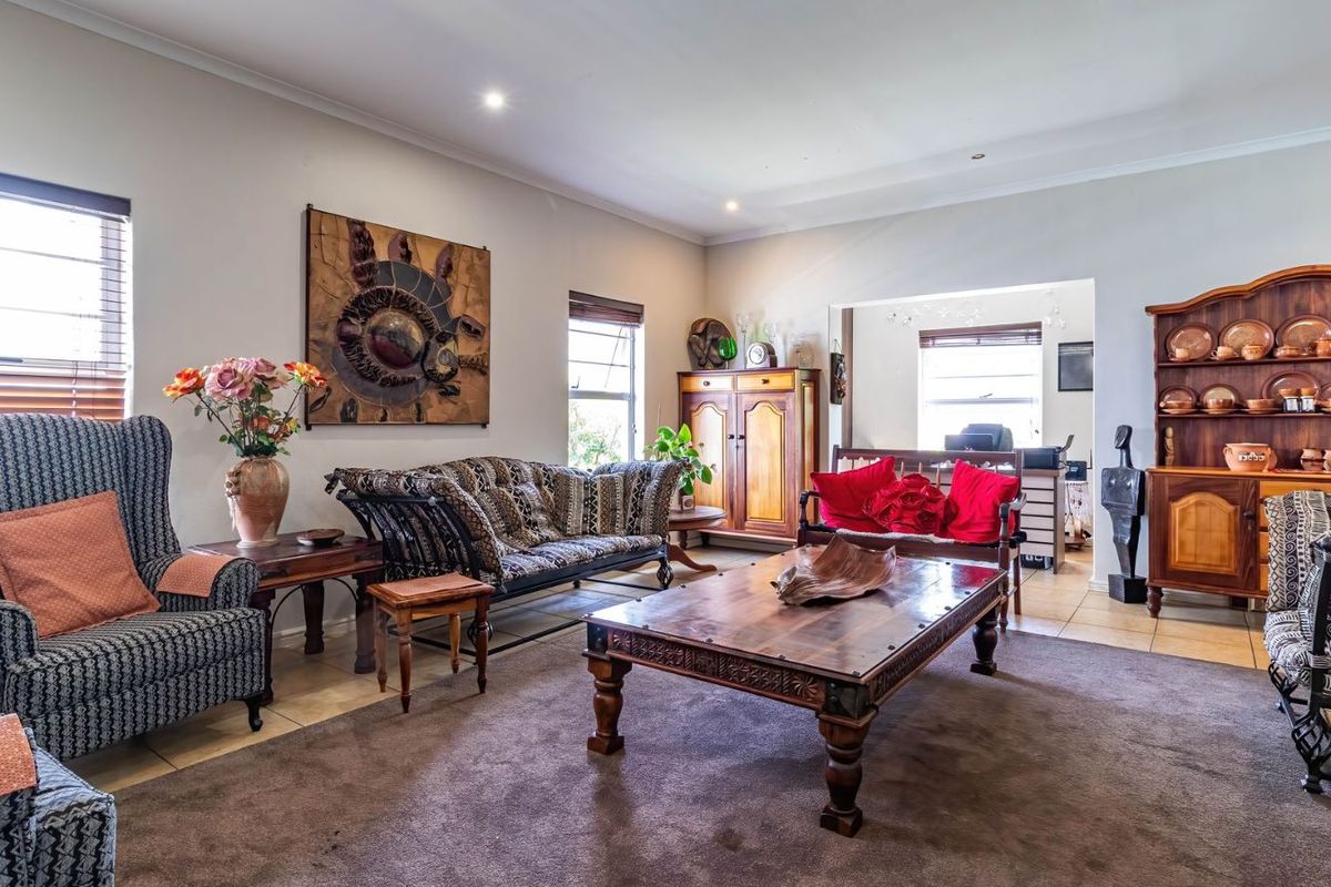A spacious living room featuring tiled flooring, recessed downlighting, and a neutral color palette, offering a comfortable and functional area for relaxation.