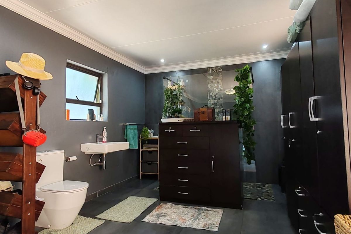 A modern bathroom featuring dark grey walls, large format floor tiles, a wall-mounted basin, and a toilet.