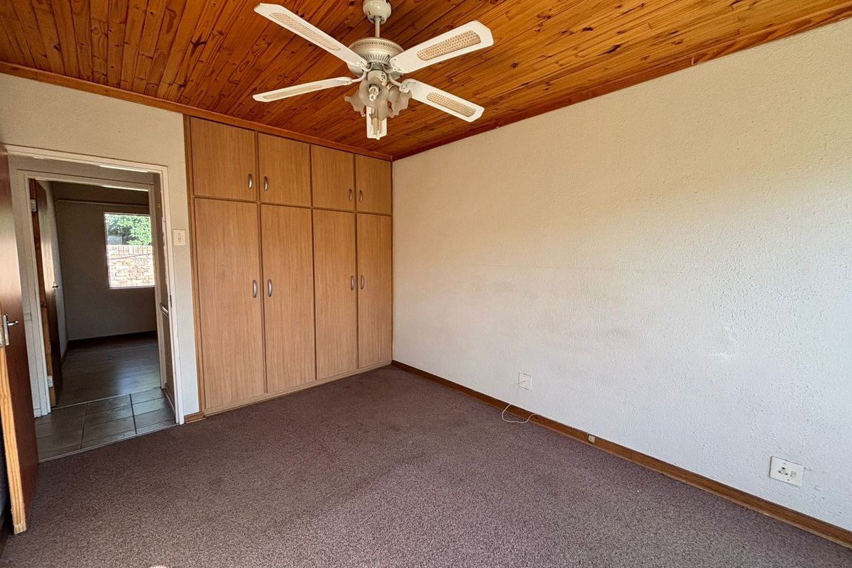 A bedroom featuring built-in wooden cupboards, a timber-clad ceiling with a ceiling fan, and carpeted flooring.