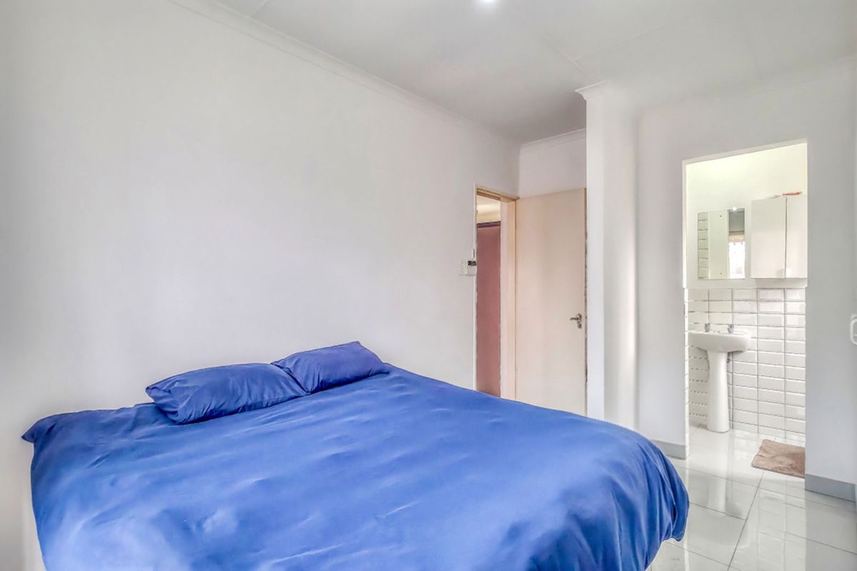 A bedroom featuring tiled flooring and an en-suite bathroom with a pedestal basin and tiled walls.