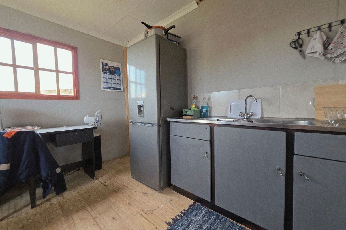 A compact kitchen area featuring basic cabinetry, a stainless steel sink, and timber flooring, suitable for a small utility or secondary kitchen space.