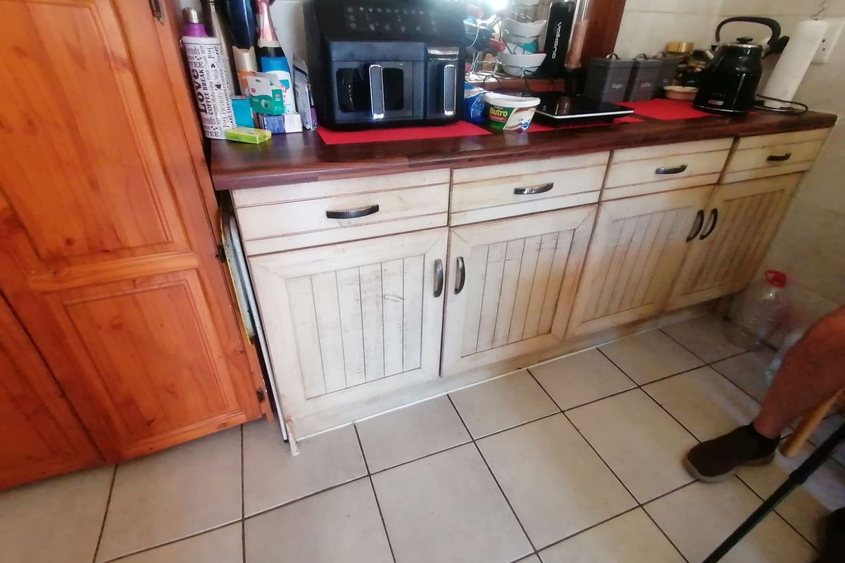 A kitchen area featuring rustic-style wooden cabinetry with a dark countertop and tiled flooring.