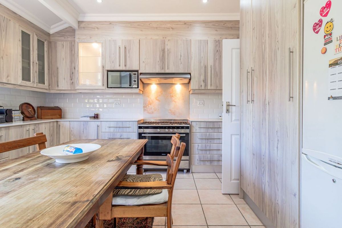 A well-maintained kitchen featuring light wood-grain cabinetry, subway tile backsplash, built-in oven with extractor fan, and tiled flooring.