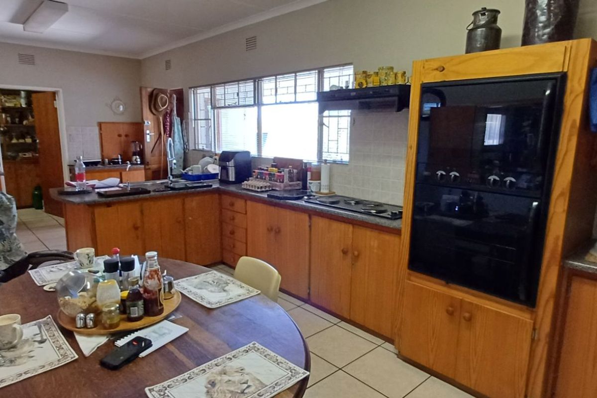 A functional kitchen featuring wooden cabinetry, a built-in oven, a hob, and tiled flooring, offering a traditional layout with ample storage space.