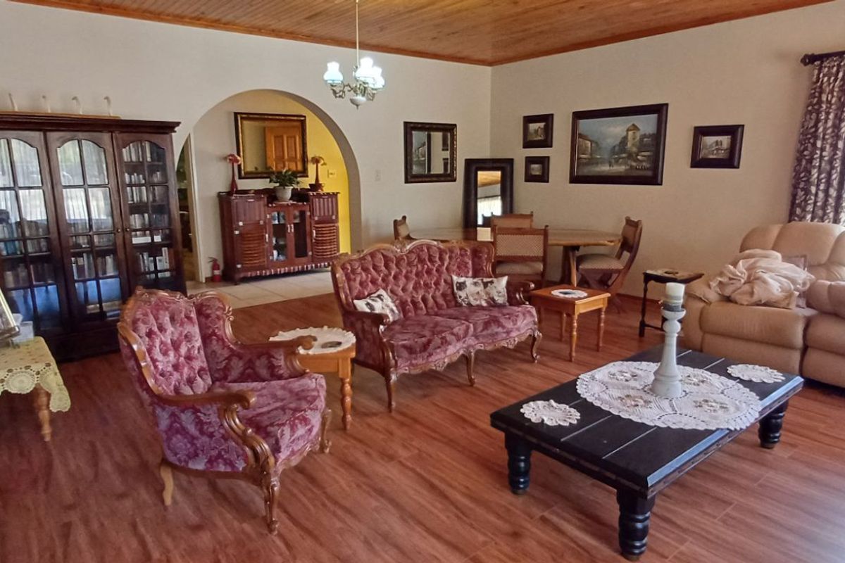 Spacious living room featuring wood-look flooring, a timber-paneled ceiling, and an arched entryway leading to an adjacent space.