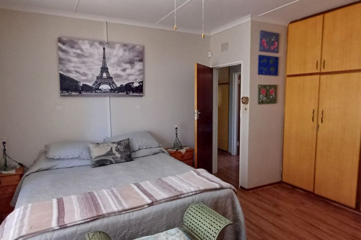 A bedroom featuring built-in wooden cupboards and laminate flooring, providing a functional and comfortable living space.