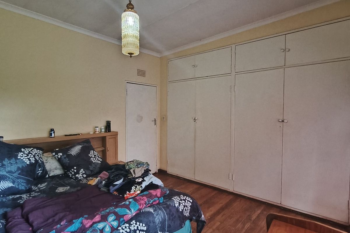 A bedroom featuring built-in floor-to-ceiling wardrobes, wooden flooring, and a classic pendant light fixture.