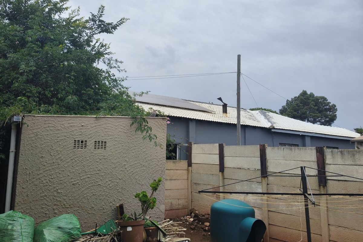 Rear view of the property showing a textured boundary wall, precast concrete fencing, and the rear roofline of the house.