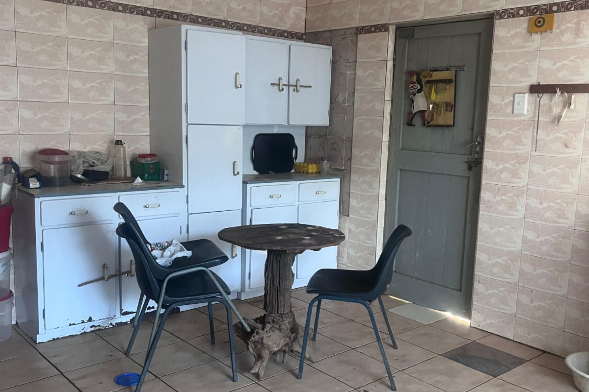 A dated kitchen area featuring built-in cabinetry, tiled walls, and ceramic floor tiles, offering a functional space with potential for modernization.
