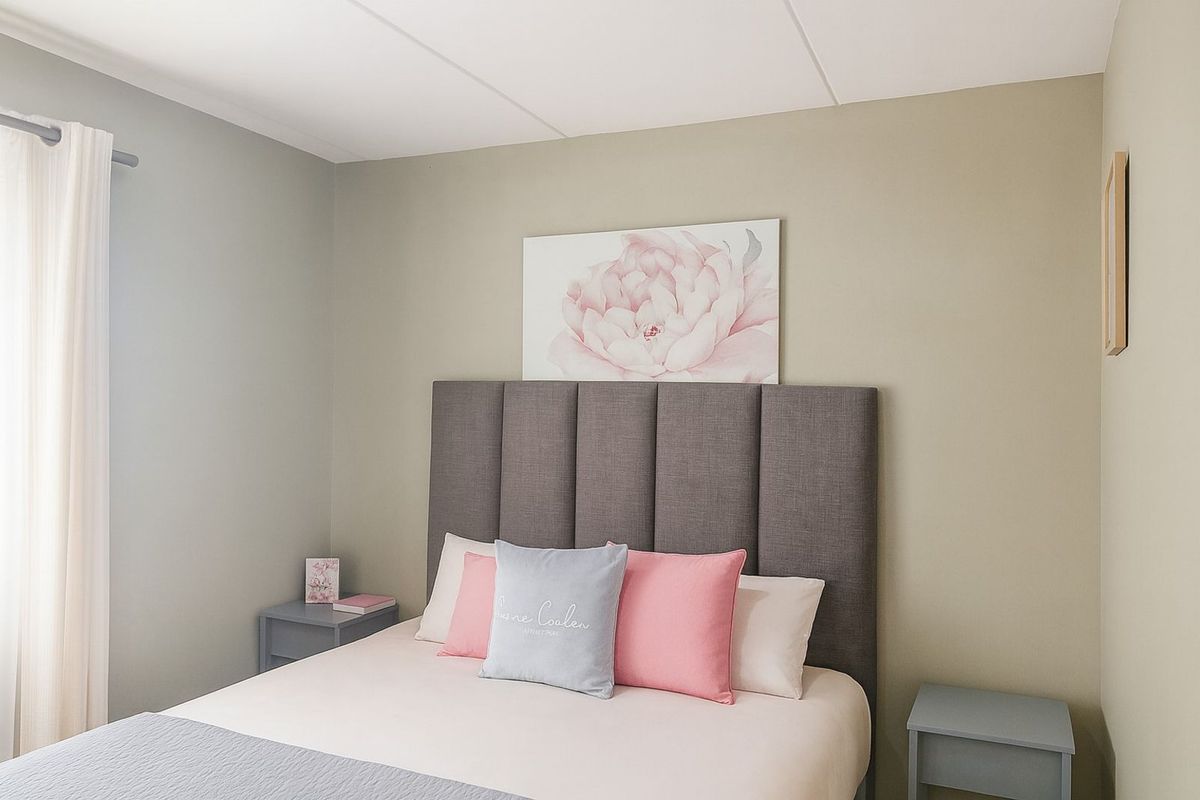 A well-maintained bedroom featuring neutral wall tones, a modern upholstered headboard, and clean finishes, providing a comfortable and inviting living space.