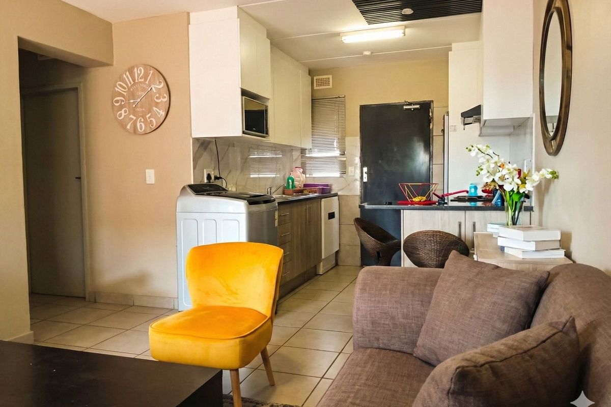 Open plan living area featuring a compact kitchen with built-in cabinetry, tiled flooring, and a breakfast counter.