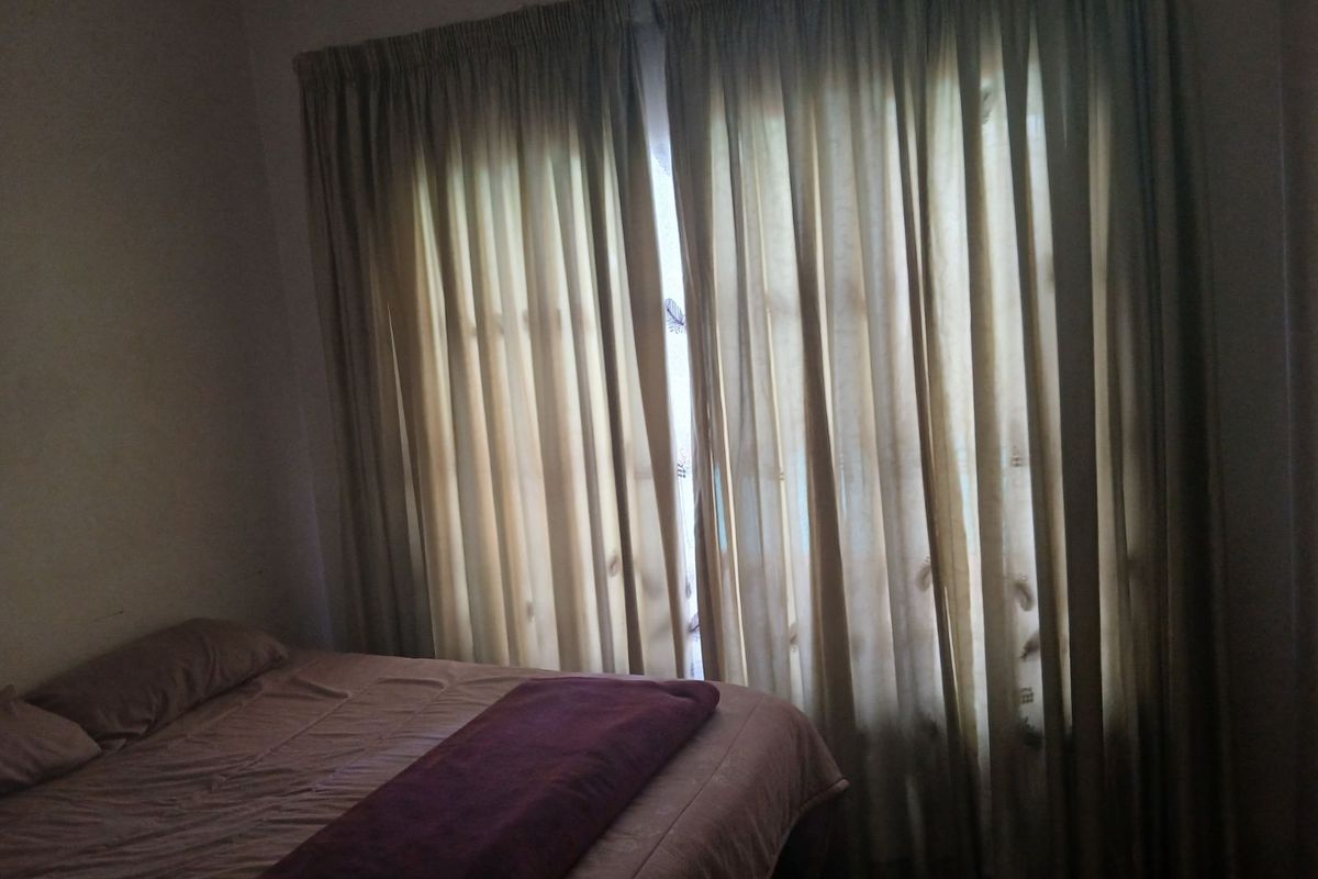 A bedroom featuring large window curtains, providing a private and cozy atmosphere.