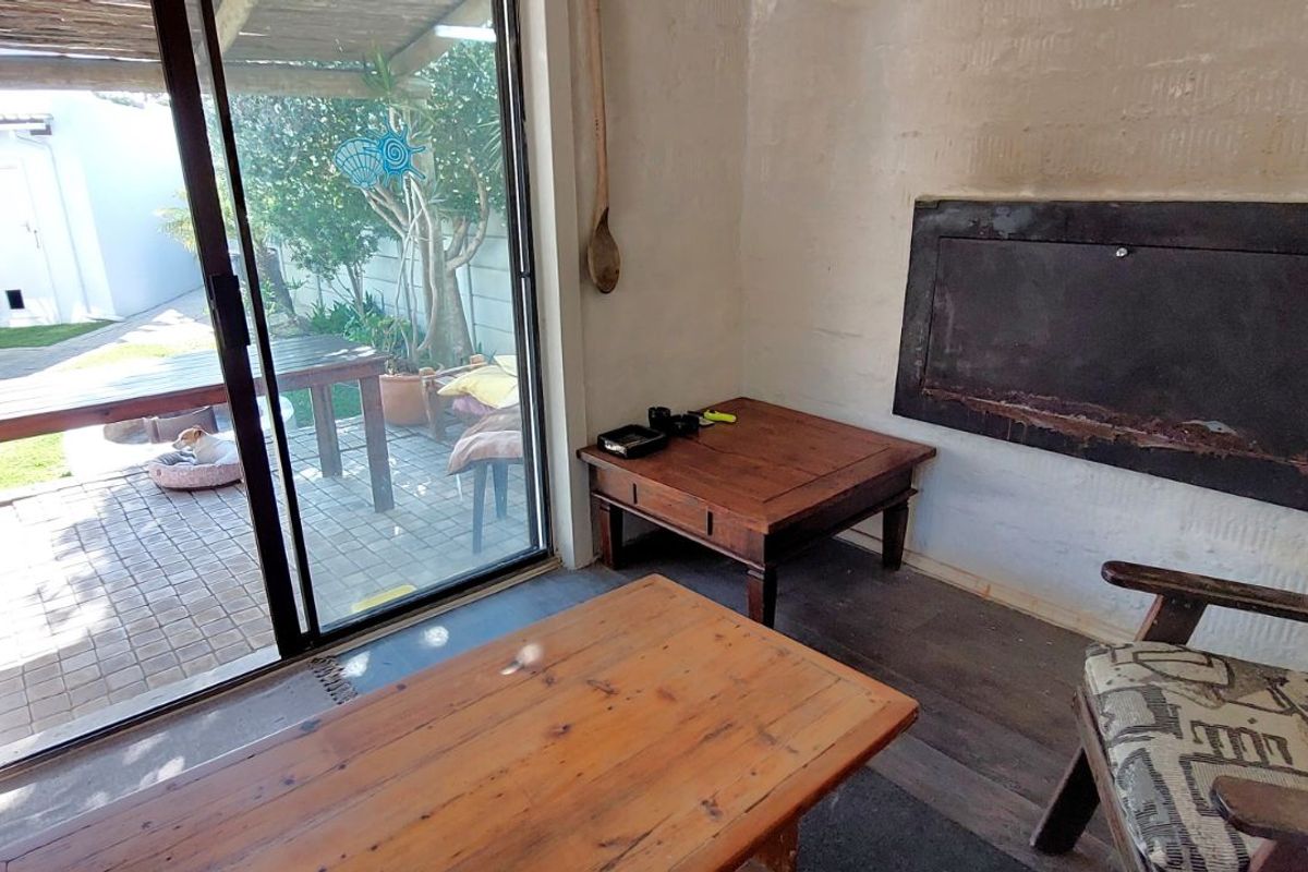 A living area featuring a built-in fireplace and sliding glass doors that open onto a paved patio and garden space.
