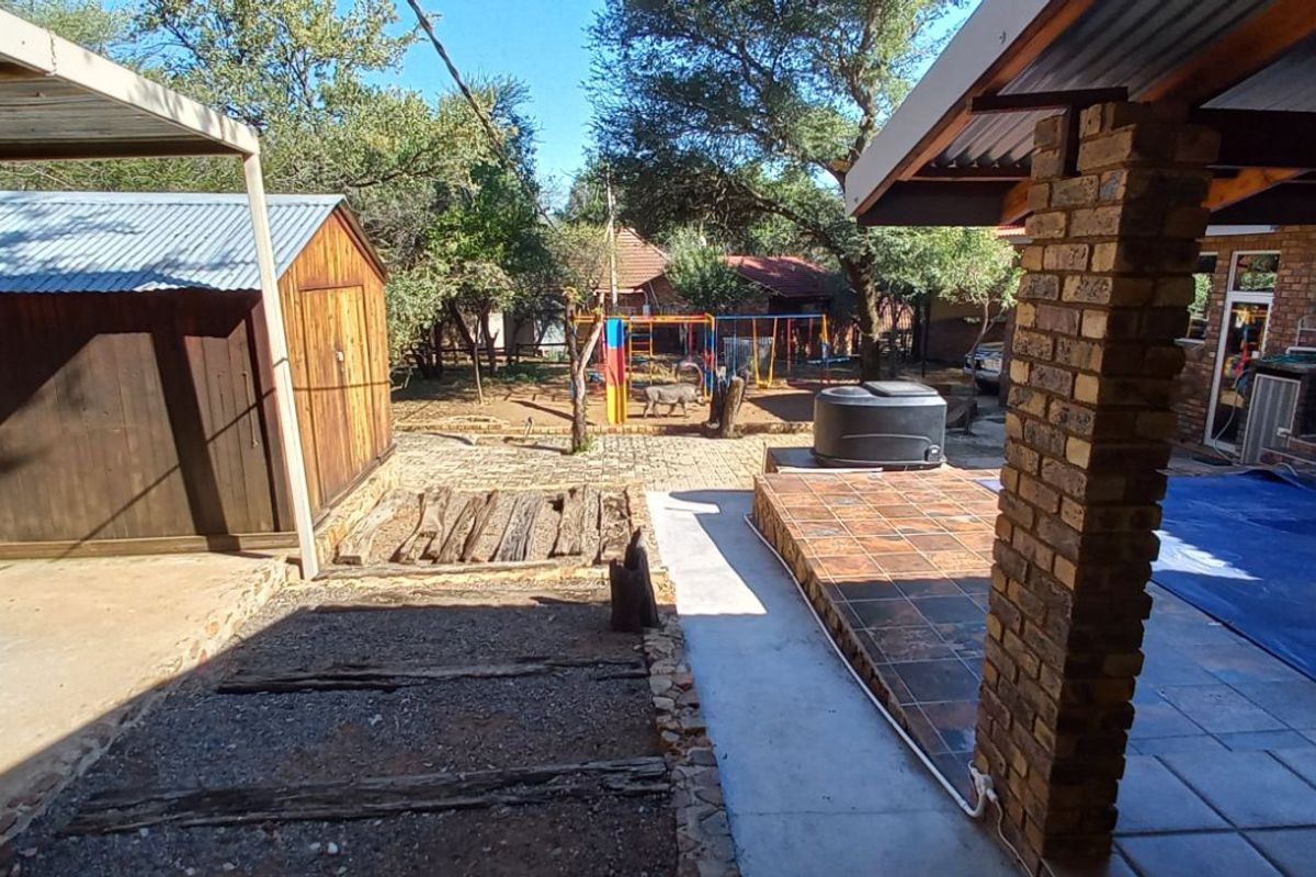Rear garden area featuring a covered patio, brick pillars, a storage shed, and a swimming pool with a safety cover.