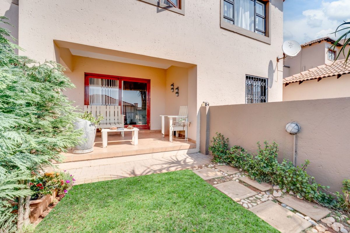 A private rear patio area featuring tiled flooring, direct access to the interior, and a small landscaped garden with paved stepping stones.