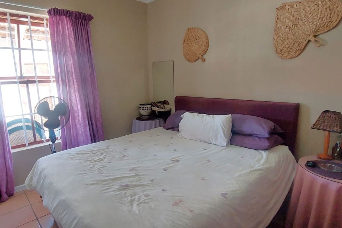 A bedroom featuring tiled flooring and a window with security bars, providing a functional and lived-in space.