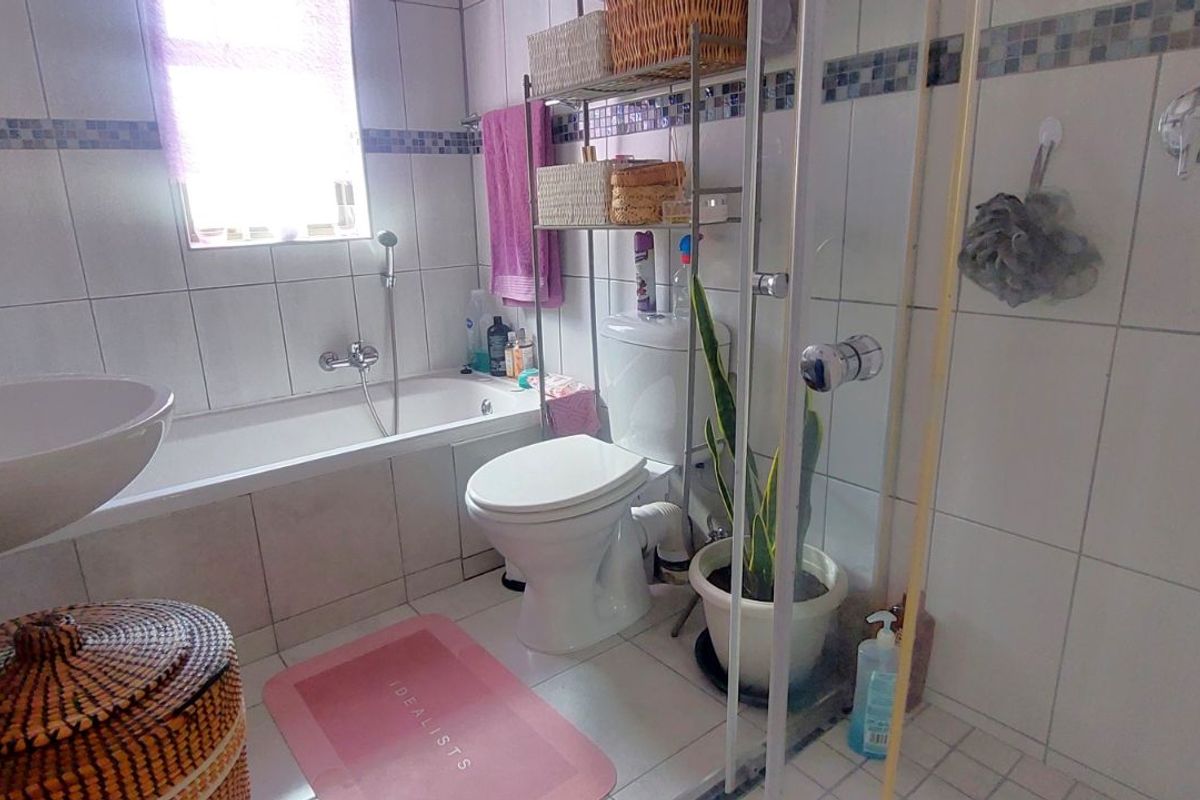 A functional bathroom featuring a bathtub, a separate shower enclosure with glass door, a toilet, and a wall-mounted basin with tiled walls.