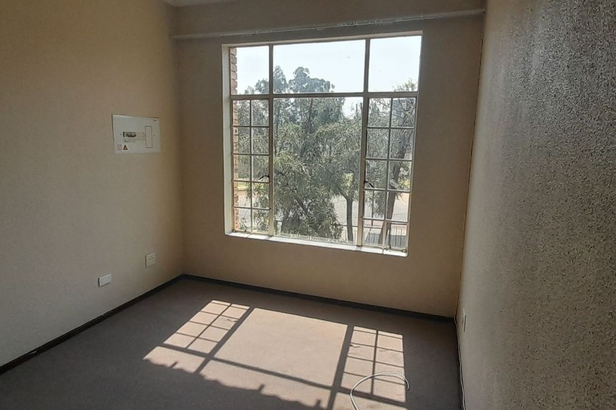 A vacant bedroom featuring a large multi-pane window, neutral wall finishes, and carpeted flooring, offering a bright and blank canvas for personalization.