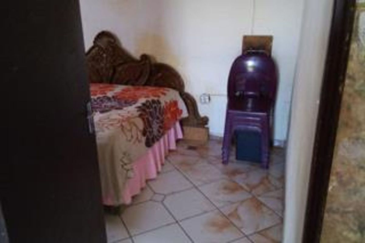 A bedroom featuring tiled flooring and basic wall finishes, viewed from the doorway.