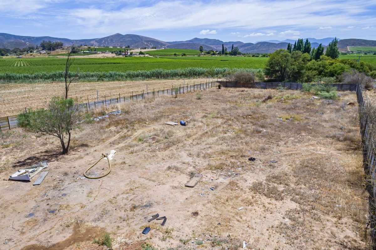An expansive, undeveloped industrial land parcel featuring perimeter fencing and scenic rural views, offering significant potential for future development or industrial use.