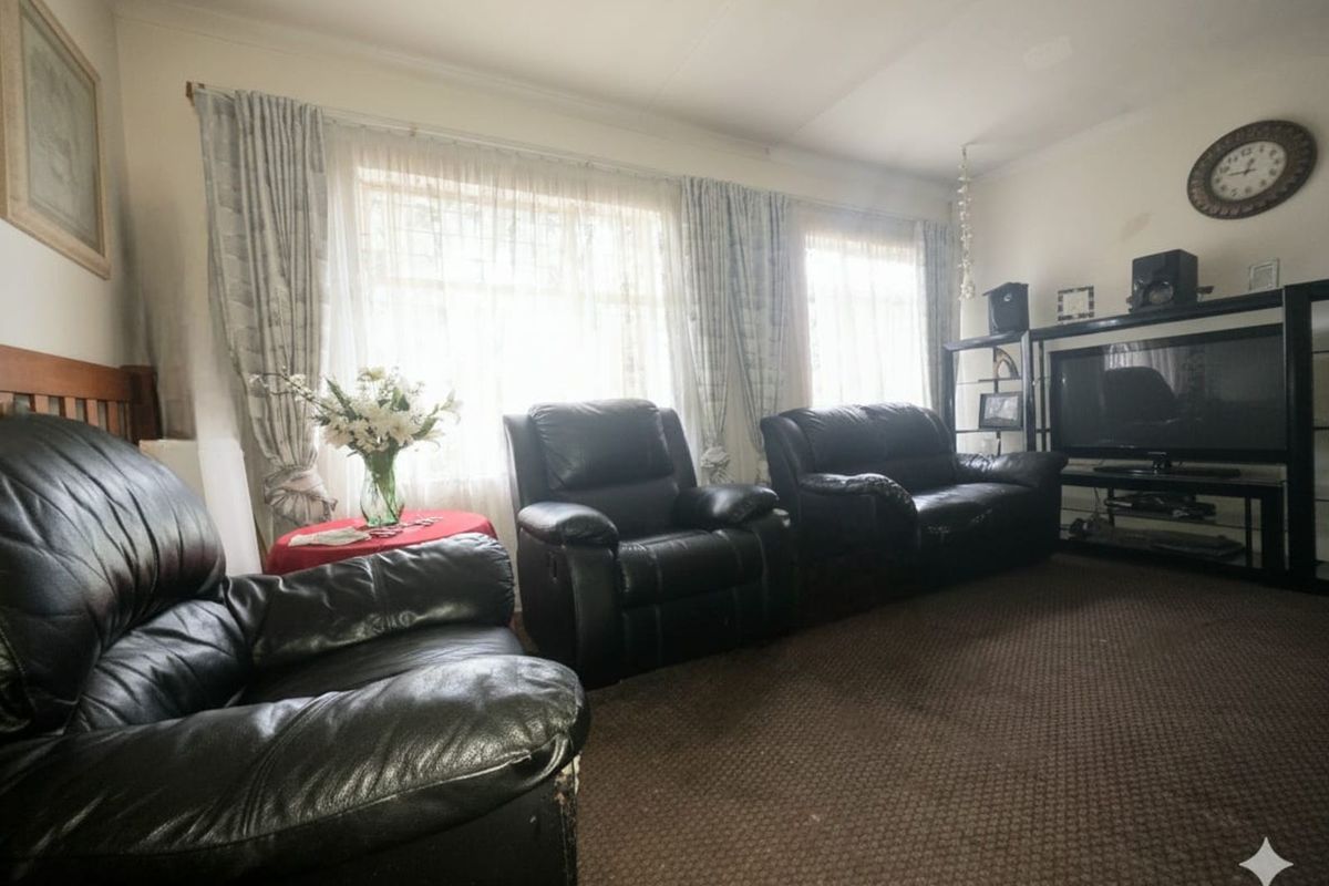 A comfortable living room featuring large windows with natural light, neutral wall finishes, and fitted carpet flooring.