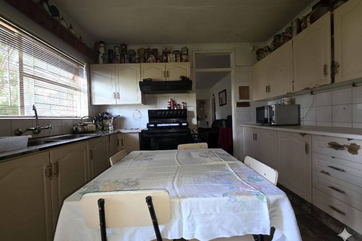 A dated kitchen featuring original cabinetry, a built-in stove with extractor fan, and a tiled splashback, offering potential for modernization and renovation.