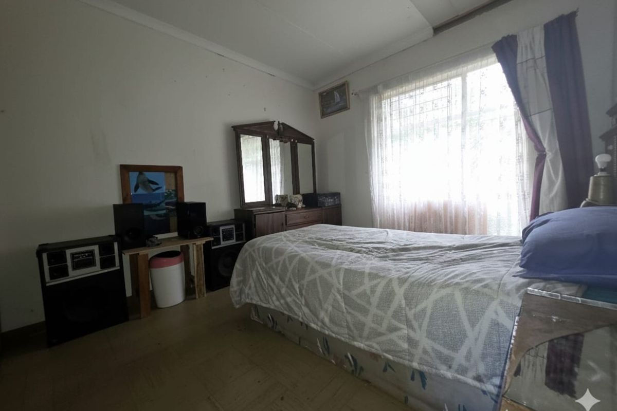 A bedroom featuring parquet flooring, large window with natural light, and standard built-in finishes.