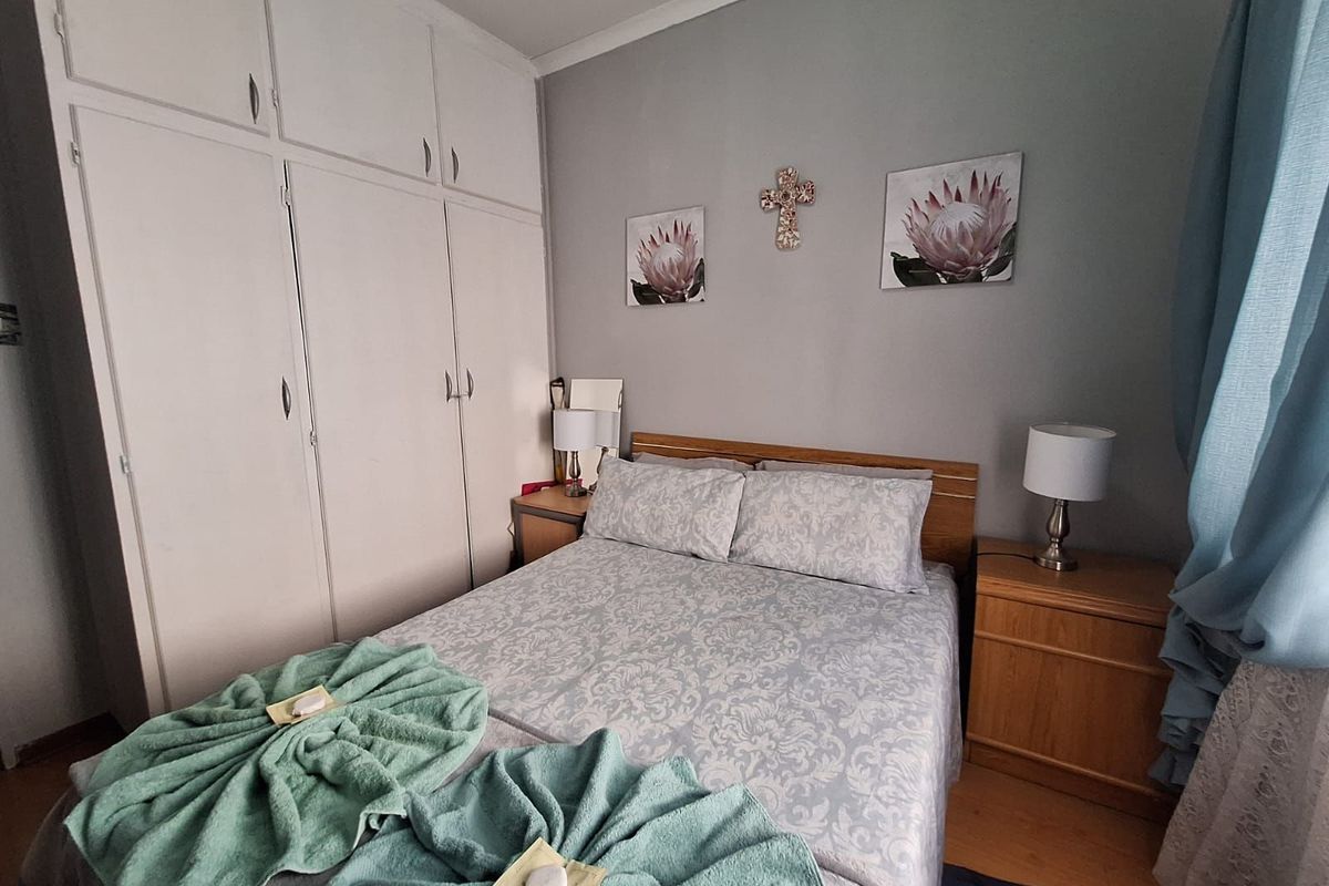A cozy bedroom featuring built-in floor-to-ceiling wardrobes and laminate flooring, providing ample storage and a functional layout.