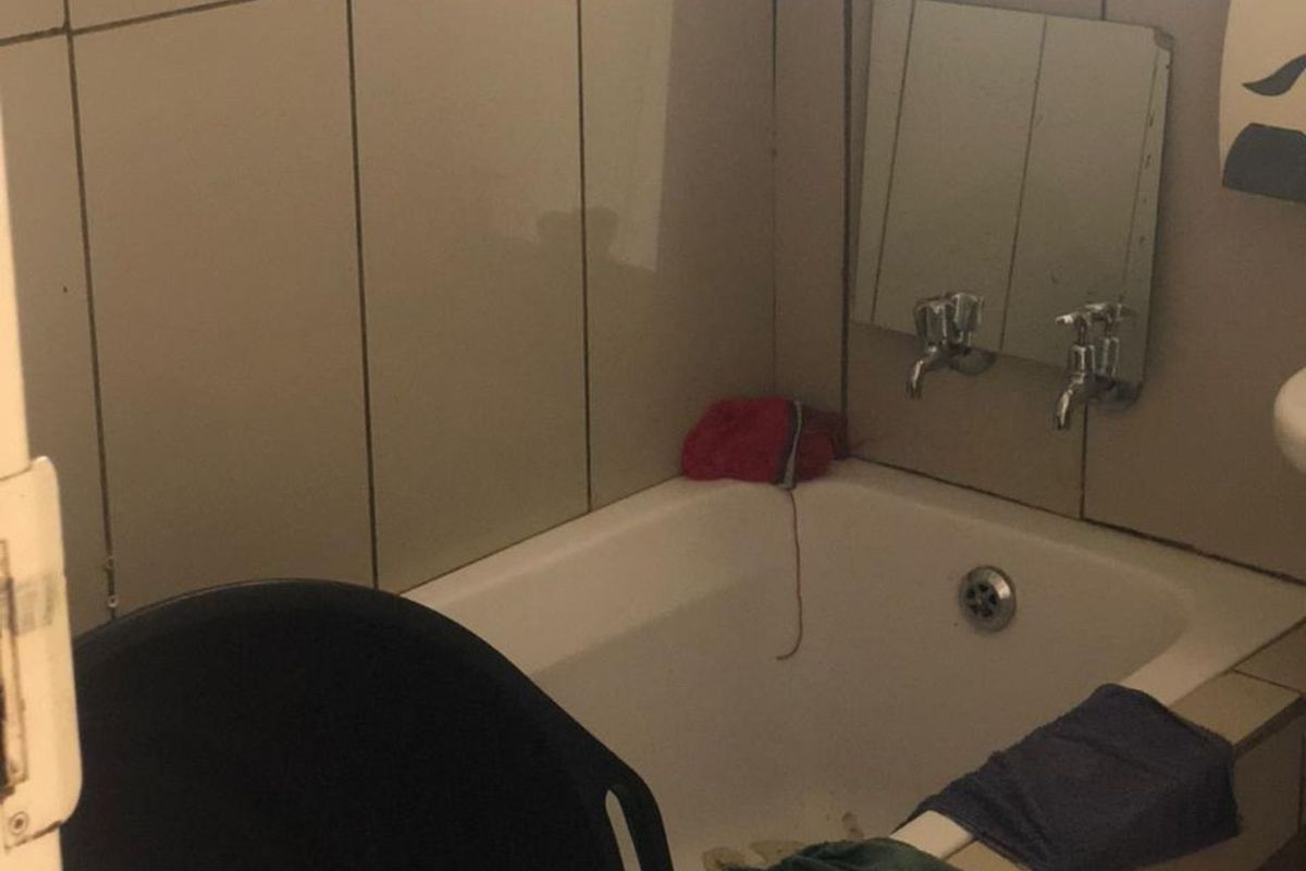 A compact bathroom featuring a built-in bathtub with wall-mounted taps and tiled wall finishes.